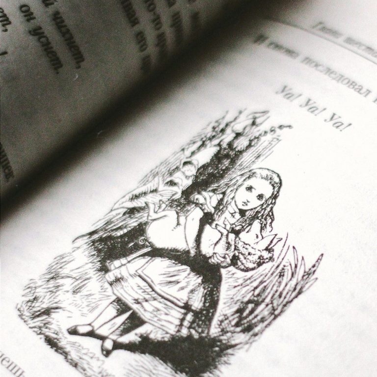 Black and white illustration from “Alice’s Adventures in Wonderland” showing Alice holding a flamingo, taken from a vintage book page.
