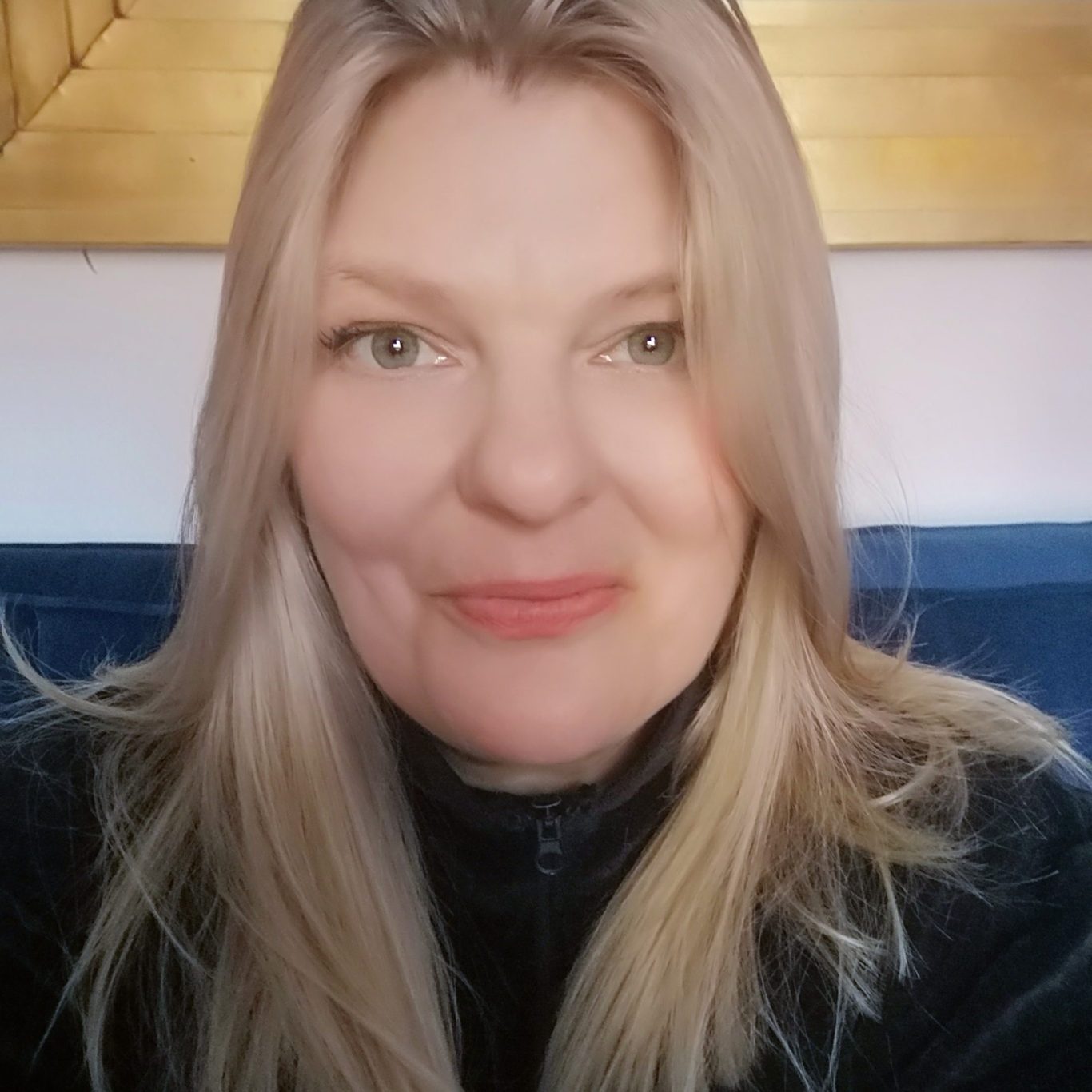 Portrait of Claire Smith, an NMH Autism Mentor with long light-blonde hair, smiling gently at the camera. Claire is seated in a calm indoor setting, wearing a dark top. The photo is cropped in a circular frame against a rich purple background with abstract lines.